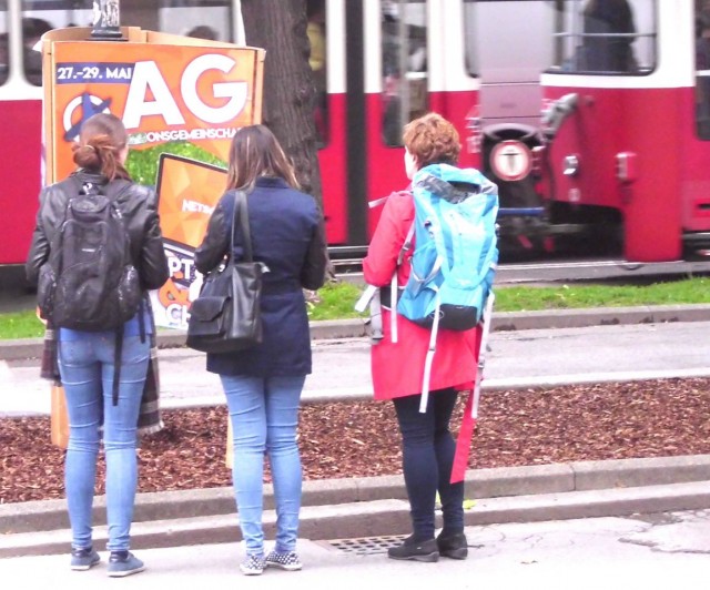 Drei Personen stehen vor einem Wahlplakat und eine Person macht ein Foto davon.